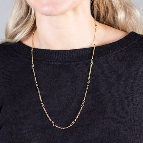 A model wears a long 18k yellow gold chain necklace dotted with black diamond beads throughout.