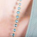 A close-up of a woven 18k yellow gold with London blue topaz beads throughout
