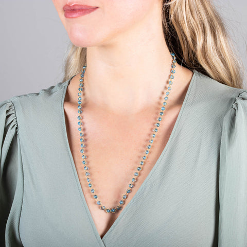 A model wears a long necklace woven with 18k yellow gold chain and London blue topaz beads throughout.