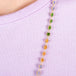 A close up of a long woven chain necklace that features Green Tourmaline, Garnet, and Tanzanite stone beads woven in 18k yellow gold chain.