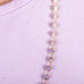 A close-up of an ombre amethyst beaded necklace woven through 18k yellow gold chain.