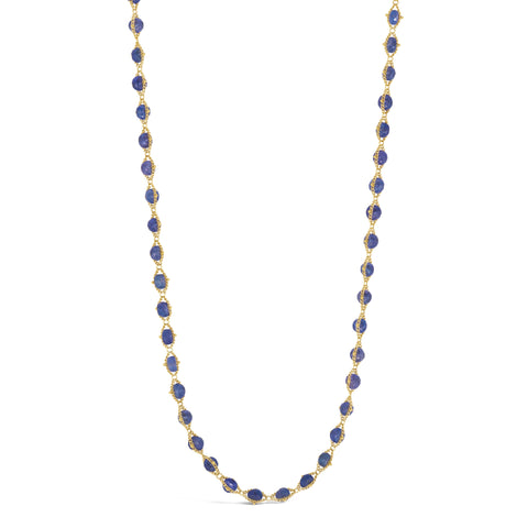 A long 18k yellow gold necklace is woven together with tanzanite beads throughout.