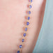 A close-up of a woven 18k yellow gold tanzanite bead necklace.
