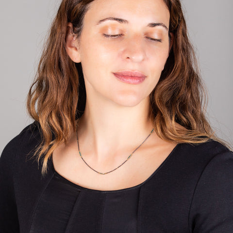 A model wears a short oxidized sterling silver chain with blue diamond and 18k yellow gold stations throughout.