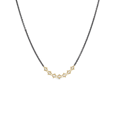 A row of small pearls is set in 18k yellow gold and are placed on an oxidized sterling silver chain.