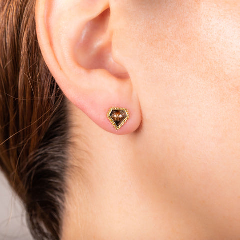 A model wears a diamond shaped champagne diamond stud earring set in an 18k yellow gold chain wrapped bezel.