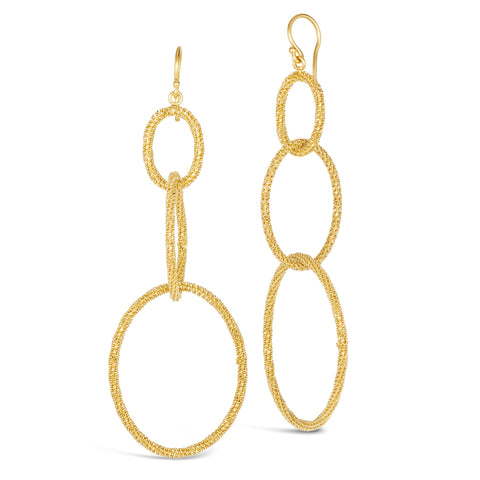 This pair of earrings features three graduated interlocking circles  crafted from a woven chain to create a stardust like effect. The earrings hang from French hook closures. 