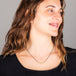 A model wears a short oxidized sterling silver chain necklace with a row of 18k yellow gold wrapped pearls in the center.