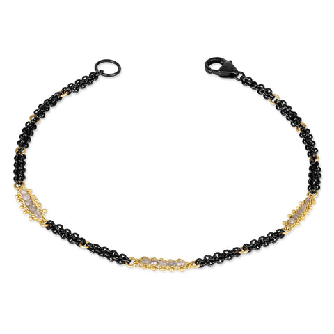 This oxidized sterling silver chain bracelet has three silver diamond and 18k yellow gold bars stationed throughout.