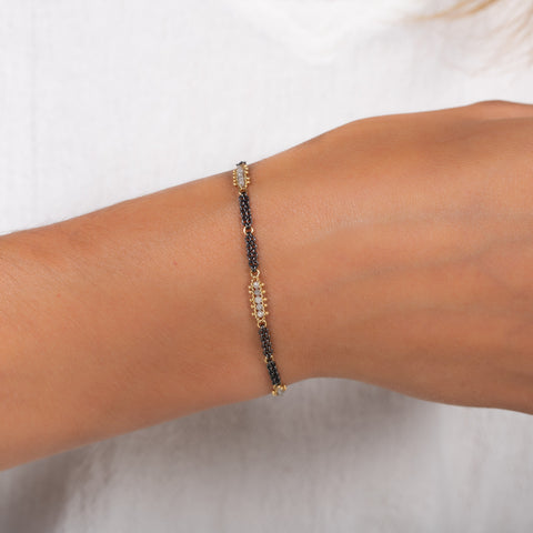 This oxidized sterling silver chain bracelet has three silver diamond and 18k yellow gold bars stationed throughout.