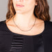 A model wears a short oxidized sterling silver necklace with stations of 18k yellow gold wrapped blue diamonds throughout.