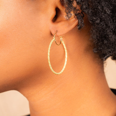 A large diamond cut chain hoop earring is crafted in 18k yellow gold and has a glimmering stardust effect.