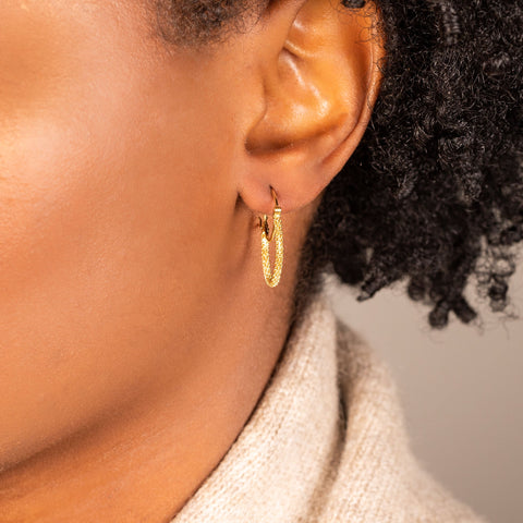 A small diamond cut chain hoop earring is crafted in 18k yellow gold and has a shimmering stardust-like effect.