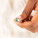 A rectangular faceted aquamarine ring is set in an 18k yellow gold chain wrapped bezel with four beaded prongs that sits on a thin band.