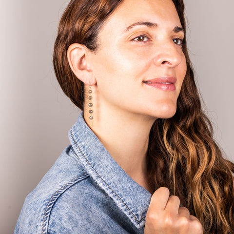 A model wears a long graduated labradorite stone earring suspended in 18k yellow gold chain.