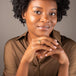 A model is wearing a small hexagon shaped charcoal colored diamond ring set in 18k yellow gold.