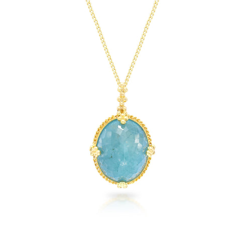 This oval aquamarine pendant is set in an 18k yellow gold chain wrapped bezel with four beaded prongs. The pendant hangs on a delicate chain.