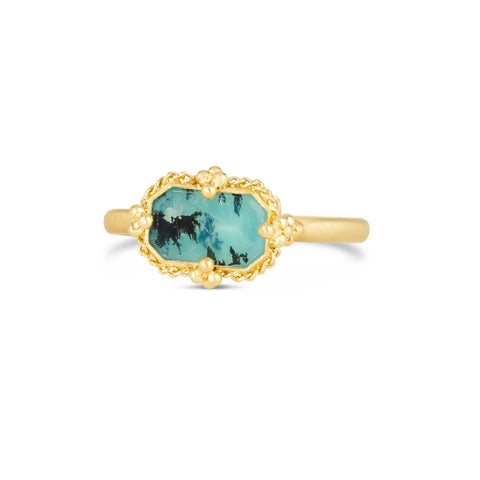 This rectangular Peruvian opal ring, with light blue hues, is set in an 18k yellow gold chain wrapped bezel with four beaded prongs. The stone sits on a thin band.