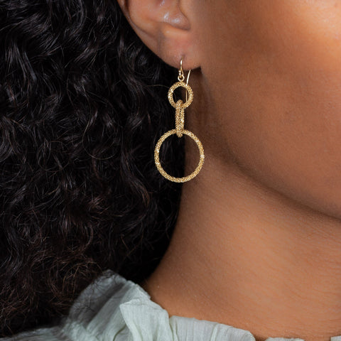 This pair of earrings features three graduated interlocking circles crafted with 18k yellow gold chain to create a stardust like effect.