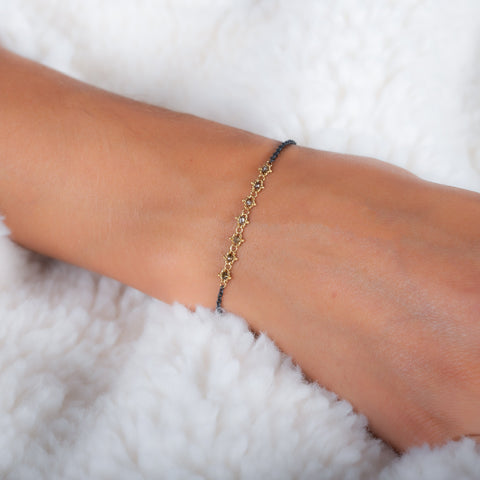 This oxidized sterling silver bracelet features a row of champagne diamonds suspended in 18k yellow gold chain in the center.