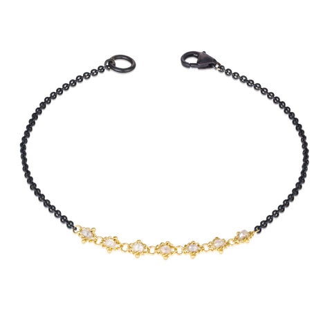This oxidized sterling silver bracelet features a row of silver diamonds suspended in 18k yellow gold chain in the center.