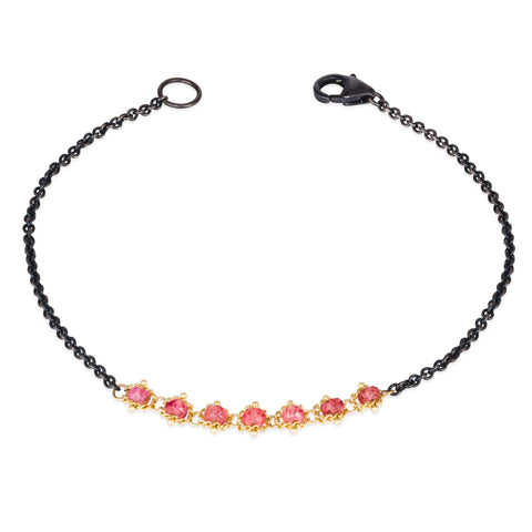 This oxidized sterling silver bracelet features a row of red spinel suspended in 18k yellow gold chain in the center.