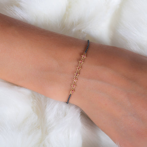 This oxidized sterling silver bracelet features a row of red spinel suspended in 18k yellow gold chain in the center.