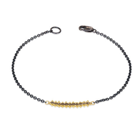 This oxidized sterling silver chain bracelet features a row of champagne diamonds suspended in 18k yellow gold chains.