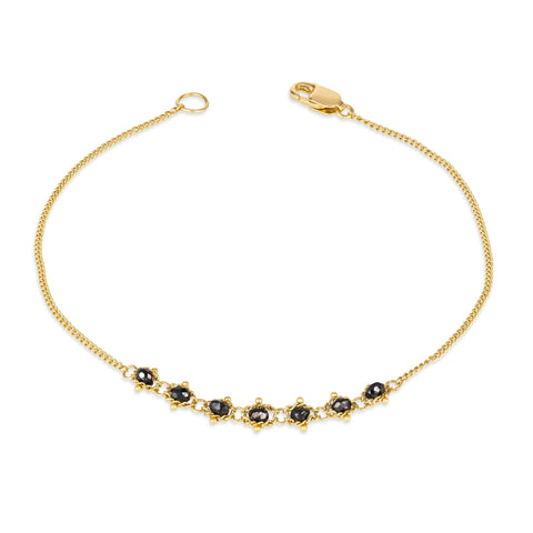 This delicate 18k yellow gold chain bracelet features a row of woven black diamonds in the center and closes with a lobster clasp.