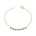 This delicate 18k yellow gold chain bracelet features a row of woven green emeralds in the center and closes with a lobster clasp.