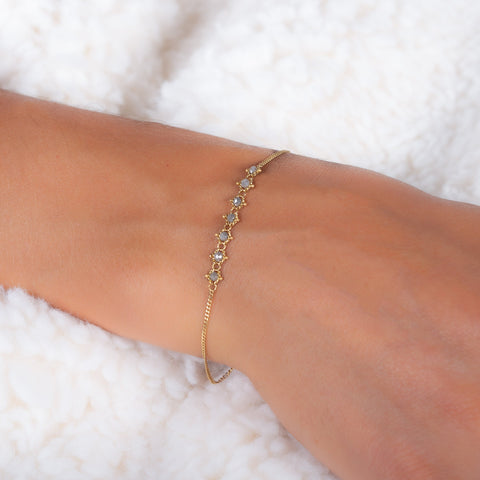 This delicate 18k yellow gold chain bracelet features a row of woven grey diamonds in the center and closes with a lobster clasp.