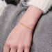 This delicate 18k yellow gold chain bracelet features a row of woven pearls in the center and closes with a lobster clasp.