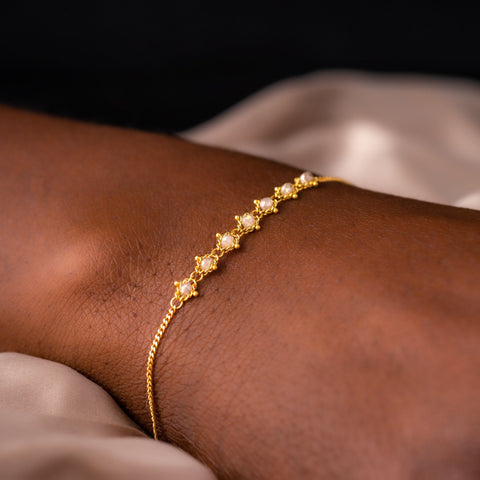 This delicate 18k yellow gold chain bracelet features a row of woven silver diamonds in the center and closes with a lobster clasp.