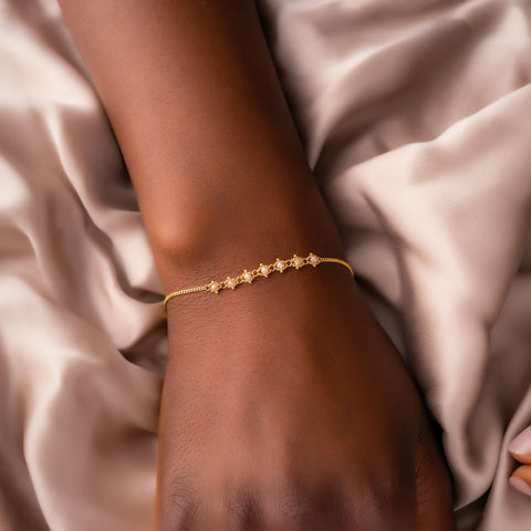 This delicate 18k yellow gold chain bracelet features a row of woven silver diamonds in the center and closes with a lobster clasp.