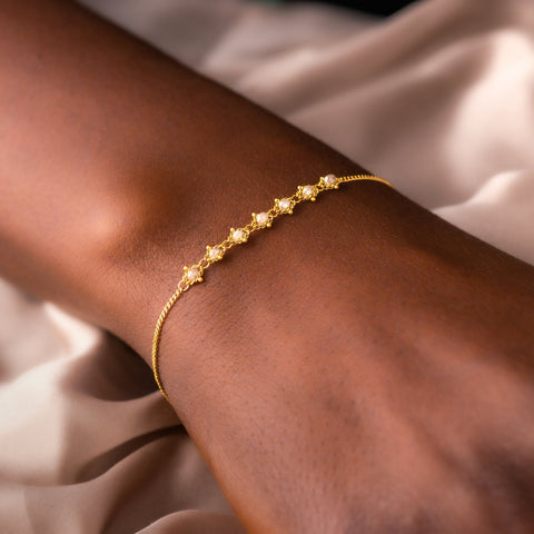 This delicate 18k yellow gold chain bracelet features a row of woven silver diamonds in the center and closes with a lobster clasp.