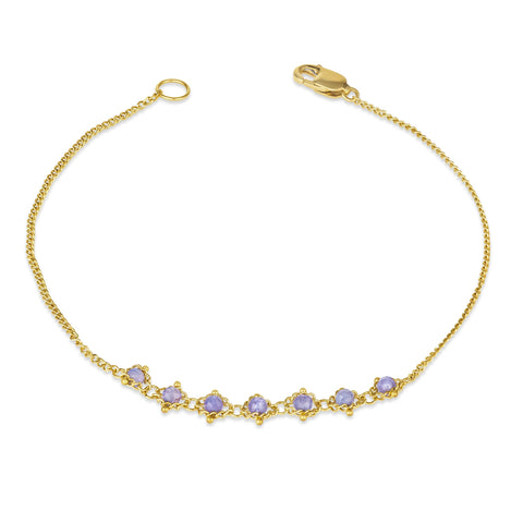 This delicate 18k yellow gold chain bracelet features a row of woven tanzanites in the center and closes with a lobster clasp.