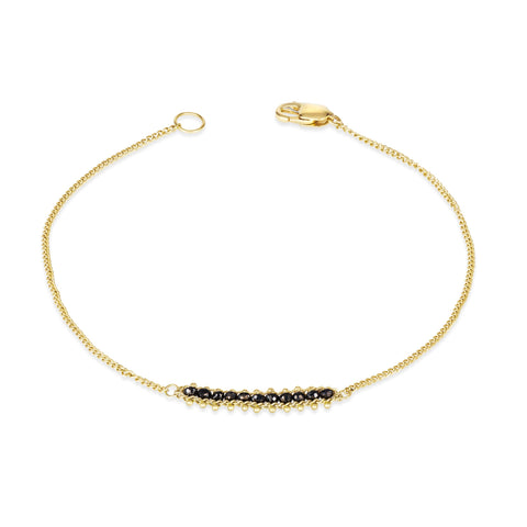 This delicate 18k yellow gold chain bracelet features a row of woven black diamonds in the center and closes with a lobster clasp.