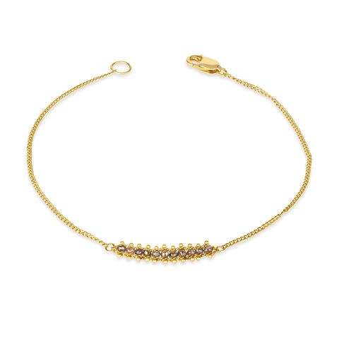 This delicate 18k yellow gold chain bracelet features a row of woven champagne diamonds in the center and closes with a lobster clasp.