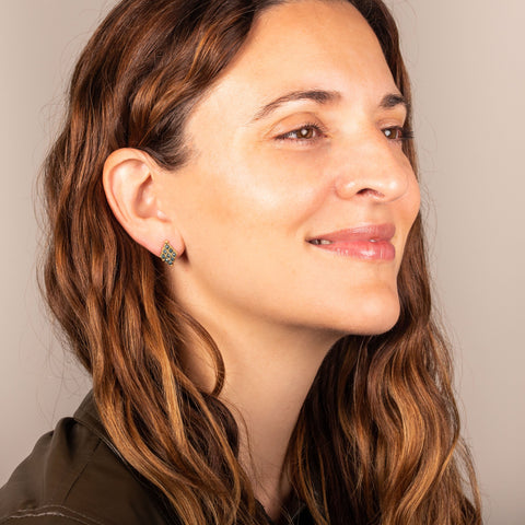 A model wears an earring crafted in 18k yellow gold chain and blue diamonds that are woven into a diamond lattice pattern and fastened with a post closure.