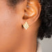 A model wears an earring crafted in 18k yellow gold chain and white pearls that are woven into a diamond lattice pattern and fastened with a post closure.