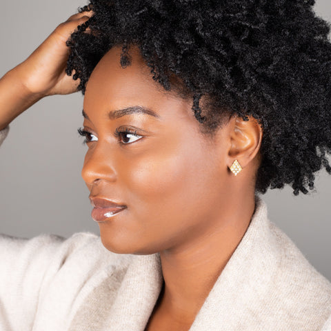 A model wears an earring crafted in 18k yellow gold chain and white pearls that are woven into a diamond lattice pattern and fastened with a post closure.