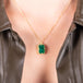 A medium faceted rectangular emerald is set in an 18k yellow gold chain wrapped bezel with four beaded prongs on a short delicate chain.