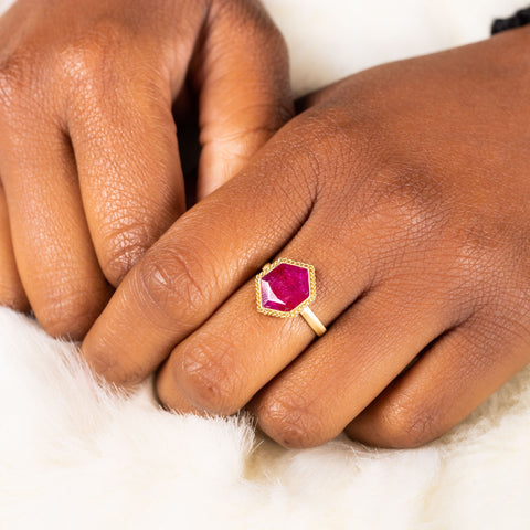 A model wears a hexagon shaped ring set in 18k yellow gold.