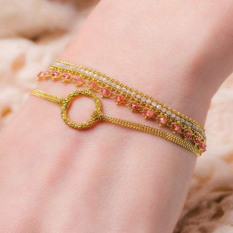 This delicate 18k yellow gold chain bracelet features a circle in the center with a stardust like effect.