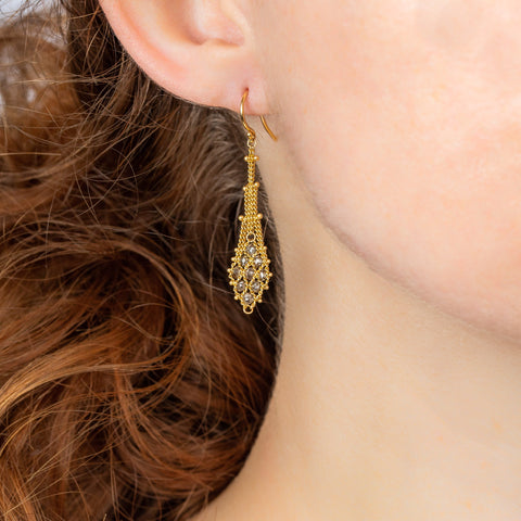 A model wears an earring crafted in 18k yellow gold chain and champagne diamonds that are woven into a diamond lattice pattern.