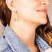A model wears an earring crafted in 18k yellow gold chain and turquoise stones that are woven into a diamond lattice pattern.