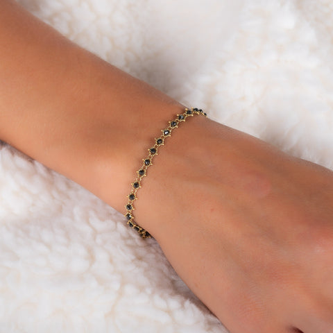 This 18k yellow gold bracelet features black diamond beads woven throughout a delicate chain.