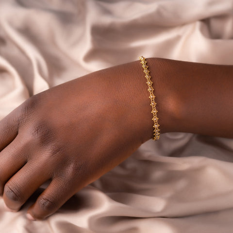 This 18k yellow gold bracelet features champagne diamond beads woven throughout a delicate chain. The bracelet features a lobster clasp closure.