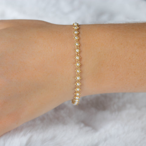 This 18k yellow gold bracelet features white pearl beads woven throughout a delicate chain. The bracelet features a lobster clasp closure.