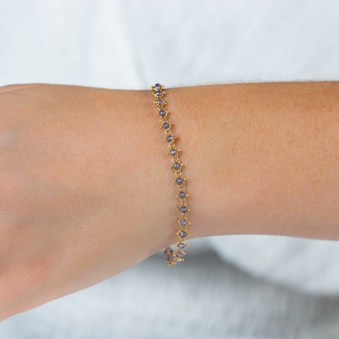 This 18k yellow gold bracelet features tanzanite beads woven throughout a delicate chain. The bracelet features a lobster clasp closure.